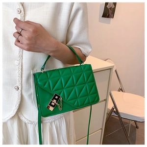 Detail view of bright green PU leather handbag with triangle quilting and gold twist lock