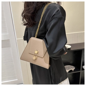 Close-up of khaki trapezoid bag with gold hexagonal clasp and metal chain strap