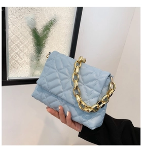 Detail of light blue quilted handbag with chunky gold acrylic chain and soft PU leather