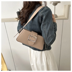 Detail view of a beige minimalist underarm bag with a large silver buckle on model