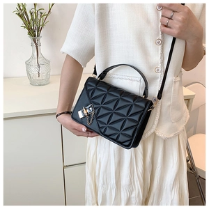 Detail shot of the quilted pattern and gold chain lock on a black crossbody bag