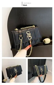 Detail of black quilted crossbody bag with golden S-shape buckle and tassel accent
