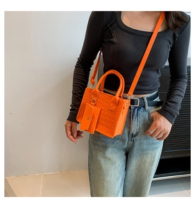 Detail of orange crocodile pattern mini felt handbag with matching small pouch and strap