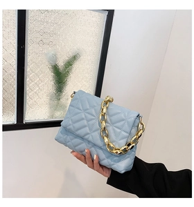 Detail of light blue quilted leather handbag with bold gold chunky acrylic chain