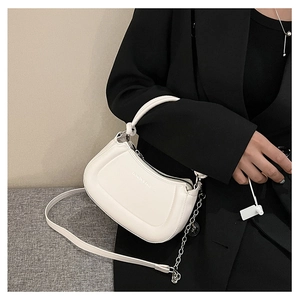 Close-up of white crossbody bag with silver decorative chain and zip closure detail