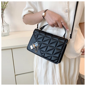 Detail of black quilted handbag with geometric triangular pattern and gold twist lock