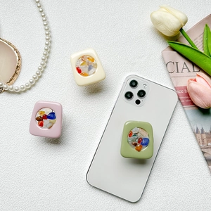Colorful gemstone expandable phone grip with transparent square design on a white surface