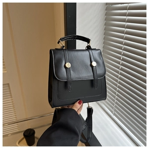 Close-up of vintage black matte leather backpack with gold hardware and top handle detail