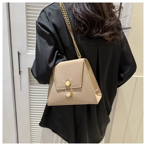 Detail view of khaki trapezoid crossbody bag featuring gold safety pin clasp and chain strap