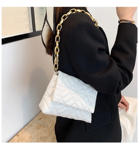 Detail of white quilted faux leather bag with chunky gold chain strap on black blazer