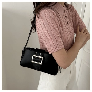 Detail of a black minimalist underarm bag featuring a large silver buckle on a model