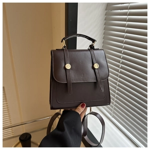 Detailed view of deep brown leather backpack with gold buckles and vertical straps