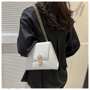 Detailed view of white trapezoid crossbody bag with gold chain strap on model