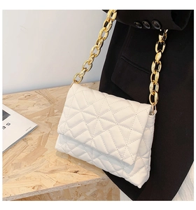 Detailed macro view of white quilted PU bag with chunky gold metal chain strap