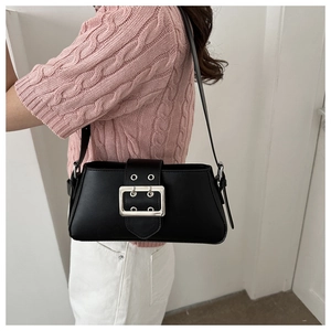Close-up of minimalist black baguette bag with silver metal buckle on the shoulder