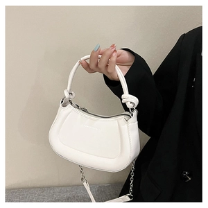 Detail of white PU leather bag featuring a round handle and fashion text on black suit