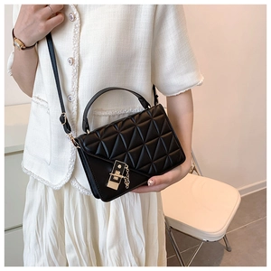Close-up of black quilted leather shoulder bag featuring a gold chain and metal clasp