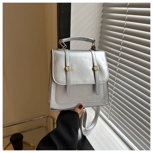 Detail of silver metallic faux leather backpack with gold buckles and top handle