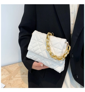 Detail of white quilted handbag with chunky gold chain strap and elegant rhombus stitching