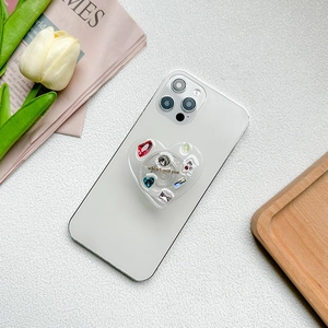 Detailed macro view of heart-shaped phone grip with multi-colored gems and rhinestones
