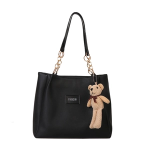 Classic black tote bag with gold chain straps and a cute beige bear charm pendant