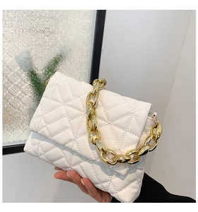 Detailed close-up of white quilted leather bag with chunky gold chain handle accessory