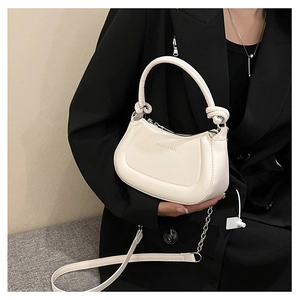 Detailed view of cream half-moon handbag featuring knotted handle and shoulder strap