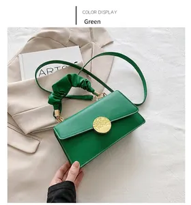 Détail de la poignée plissée verte et du fermoir en métal doré sur un sac à bandoulière