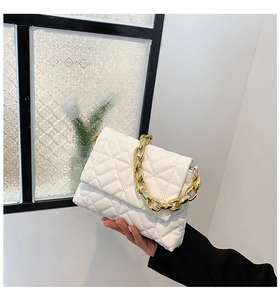 Detail of white quilted PU leather handbag featuring a bold gold acrylic chain handle