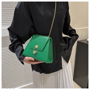 Close-up of emerald green trapezoid bag featuring gold chain and geometric clasp detail