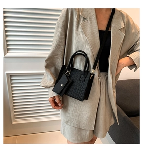 Detail of black crocodile texture handbag with matching mini pouch and detachable shoulder strap