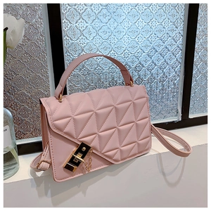 Detailed view of pink quilted handbag with gold clasp on white windowsill