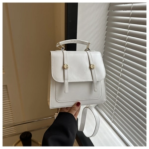 Detail of minimalist white faux leather handbag with golden round buckle and top handle