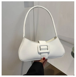 Close-up of white faux leather baguette bag featuring a stylish large square buckle detail