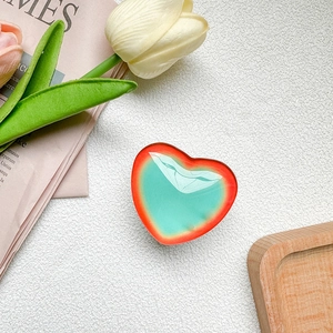Detail of red and green gradient heart phone grip with glossy jelly texture on tray