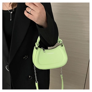 Detail of lime green leather saddle bag with chain strap and FASHION & BAGS print