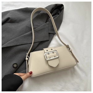 Close-up of beige shoulder bag with silver buckle detail on a gray blazer background