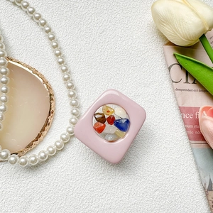 Detail of pink square phone grip with colorful polished gemstones and transparent window