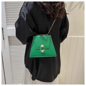 Detail of bright green trapezoid bag with gold geometric lock and chain strap