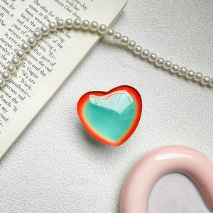 Detail view of heart-shaped gradient phone grip on a white textured background