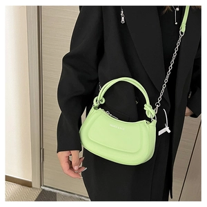 Detail of light green crescent bag with silver chain strap shown on black blazer