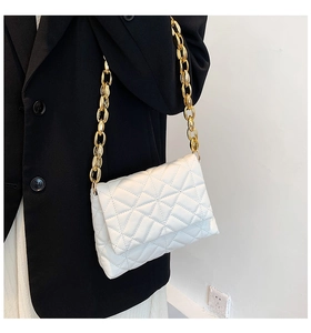 Detail of white quilted faux leather shoulder bag featuring chunky gold acrylic chain strap