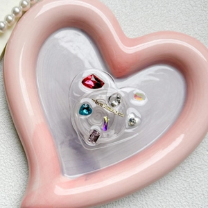 Detail of heart-shaped phone grip featuring colorful rhinestones on a ceramic tray