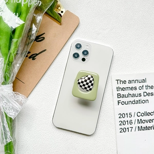 Detail of green heart checkered phone grip mounted on a white smartphone on desk