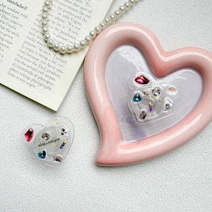 Macro shot of heart-shaped phone grip with colorful rhinestones and gold text on a desk