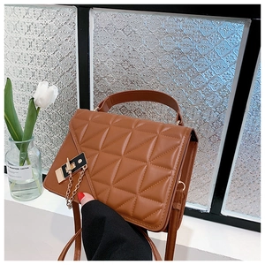 Detailed view of warm brown quilted PU leather handbag with gold metal clasp and chain