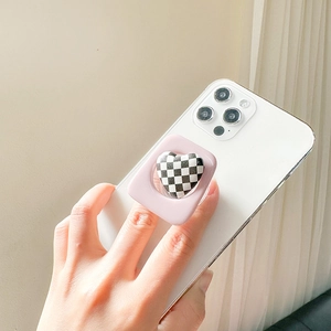 Close-up of pink heart-shaped checkerboard phone grip on white smartphone case