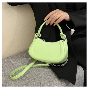 Detail of light green crescent leather bag featuring silver chain and metal hardware