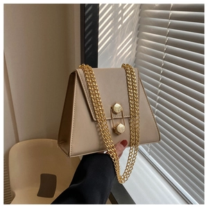 Detail of light beige trapezoid bag featuring gold hexagonal locks and chain strap