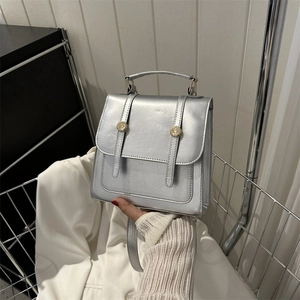 Minimalist silver metallic backpack with dual vertical straps and golden hardware buckles